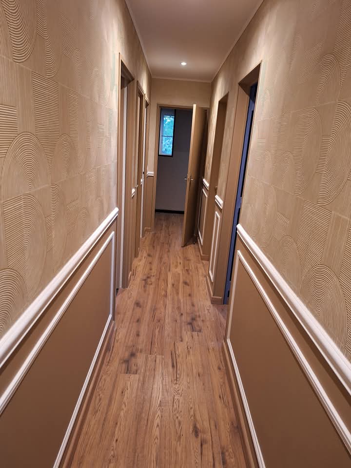 Couloir beige avec papier peint texturé et moulures